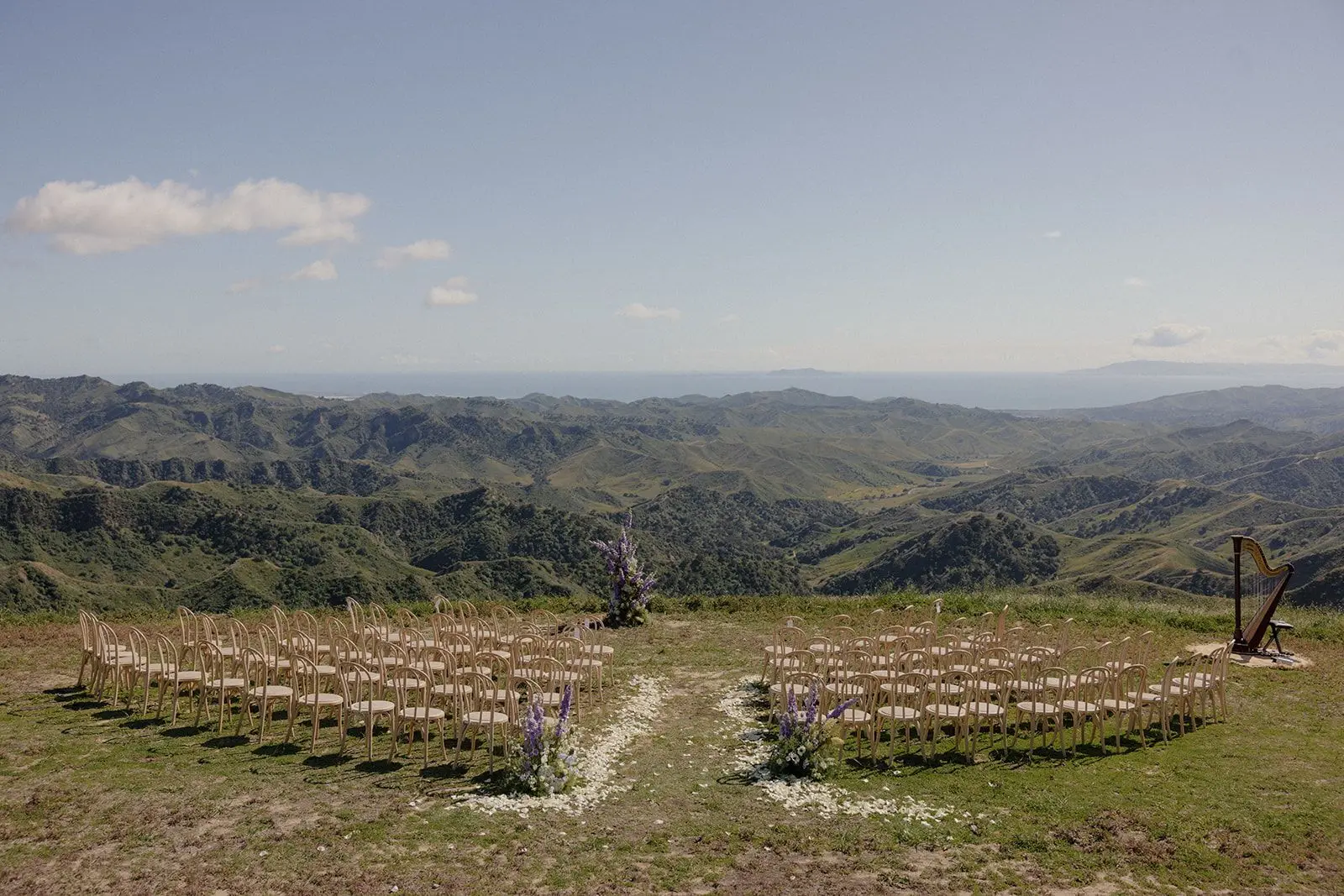 Rows of bentwood chairs arranged in a wide arc on a grass ridge high above the Ojai valley, a harp at the head of the aisle and the Pacific on the horizon.