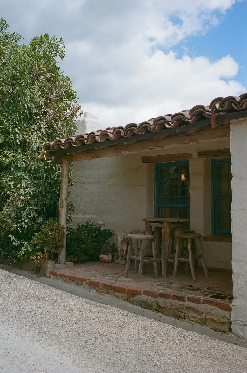 A whitewashed casita with a terracotta tile roof and blue-painted window frames, shot on film.