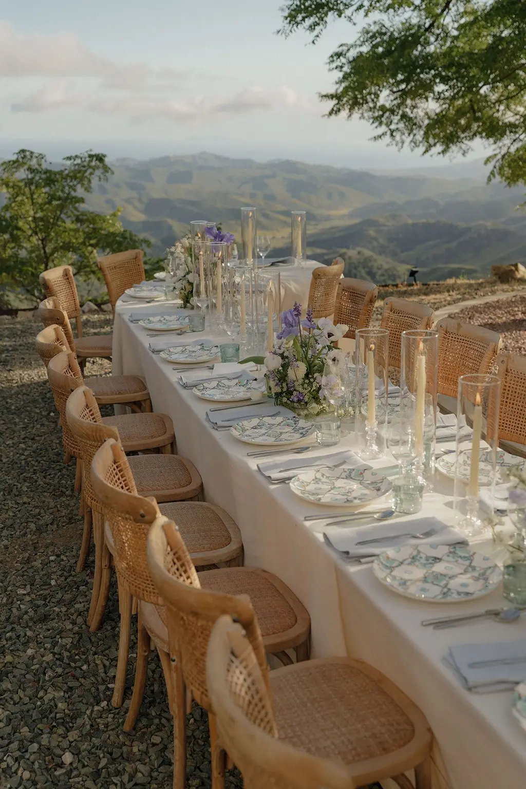 The reception table laid end to end with patterned china, glassware and lavender stems, looking out over the ridge.